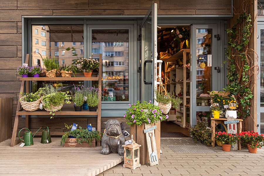 Business Insurance - Small Flower and Gift Shop on a Brick Path, Charming Items Like Watering Cans and Baskets of Herbs on Display