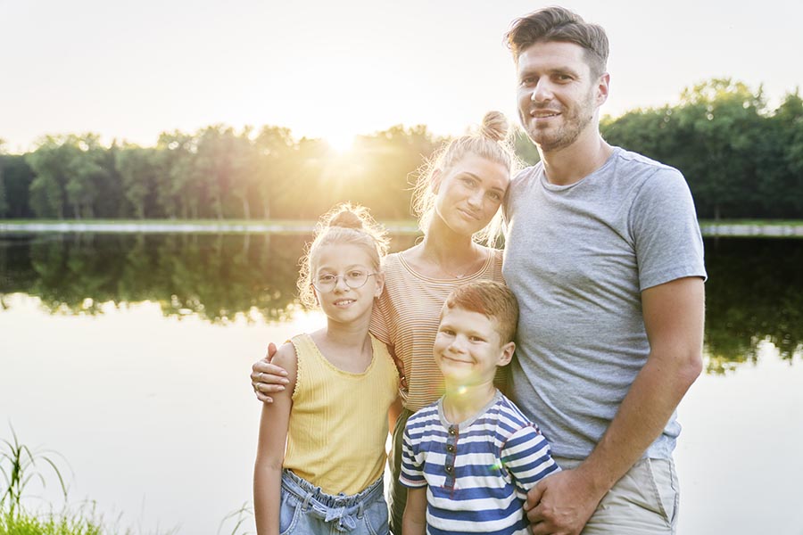 Personal Insurance - Family of Four Standing by a Small Lake at Sundown
